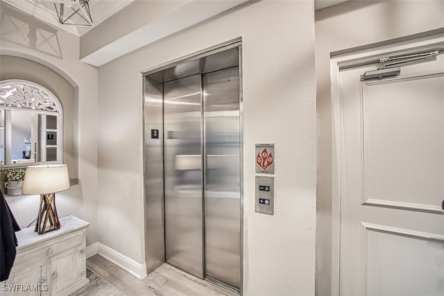 kitchen featuring baseboards, light countertops, light wood-type flooring, and elevator