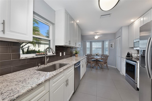 kitchen featuring white cabinetry, sink, light tile patterned floors, light stone counters, and stainless steel appliances