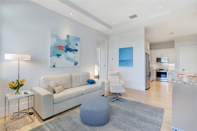 living room featuring a raised ceiling and light wood-type flooring