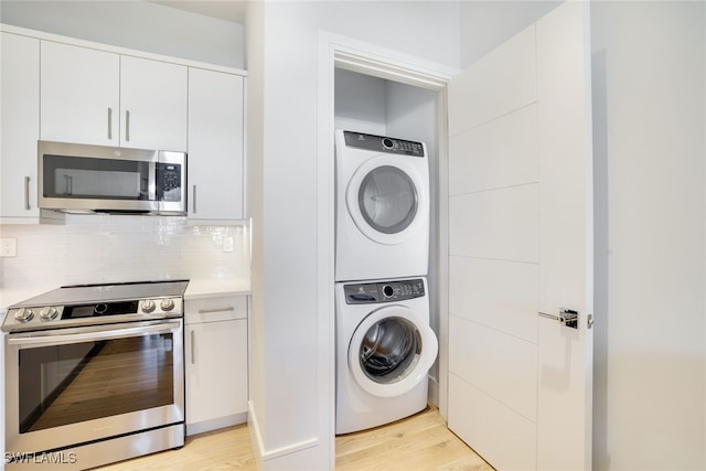 laundry room with stacked washer / drying machine and light wood-type flooring