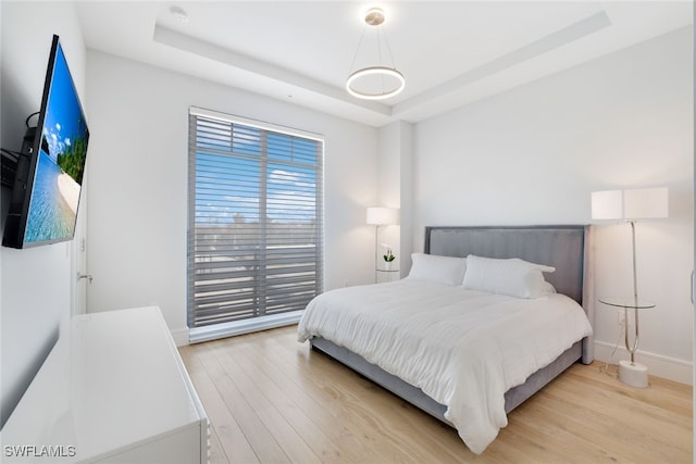 bedroom featuring light hardwood / wood-style floors and a raised ceiling