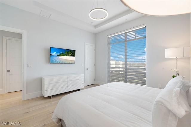 bedroom featuring a tray ceiling and light wood-type flooring