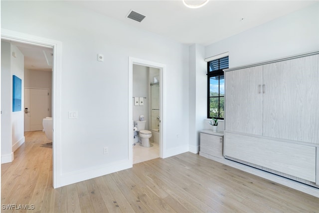 unfurnished bedroom with ensuite bathroom and light hardwood / wood-style floors