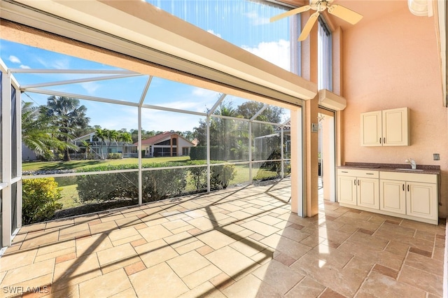 unfurnished sunroom featuring ceiling fan, a wealth of natural light, and sink