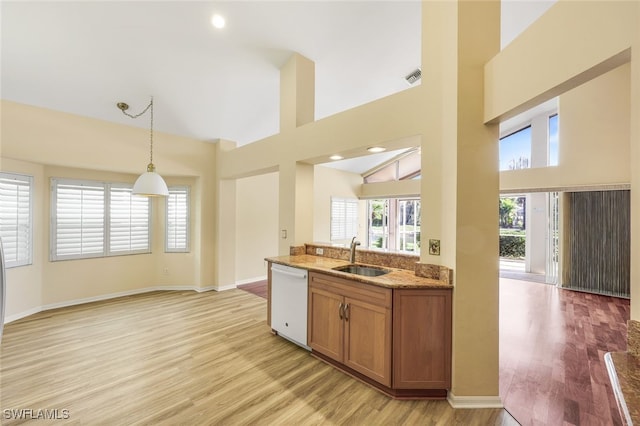 kitchen with sink, light stone counters, white dishwasher, pendant lighting, and light hardwood / wood-style floors