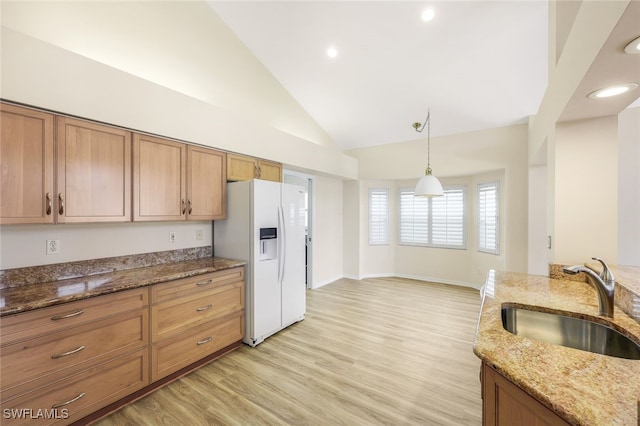 kitchen featuring sink, decorative light fixtures, light wood-type flooring, white fridge with ice dispenser, and stone countertops