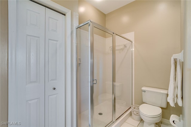 bathroom featuring tile patterned floors, toilet, and an enclosed shower