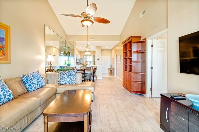 living room with ceiling fan, light wood-type flooring, and high vaulted ceiling