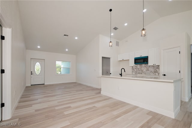 kitchen with white cabinets, sink, hanging light fixtures, light hardwood / wood-style flooring, and decorative backsplash