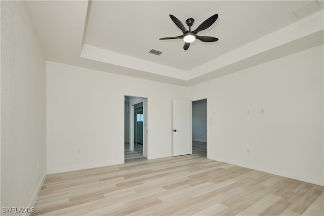 spare room featuring ceiling fan, a raised ceiling, and light hardwood / wood-style flooring
