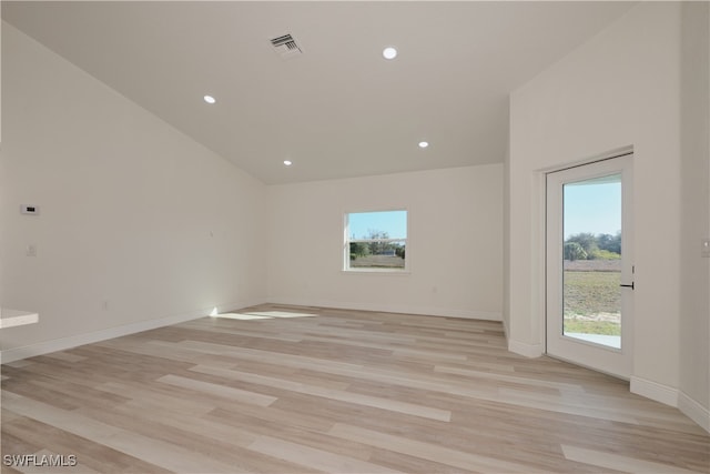 spare room featuring vaulted ceiling and light hardwood / wood-style flooring