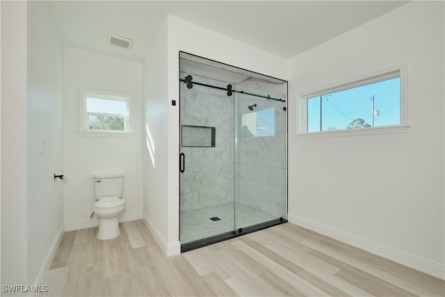 bathroom with wood-type flooring, a shower with shower door, and toilet