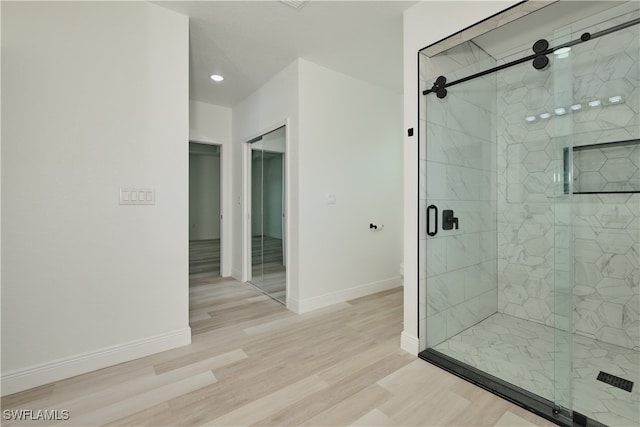 bathroom with hardwood / wood-style flooring and a shower with shower door