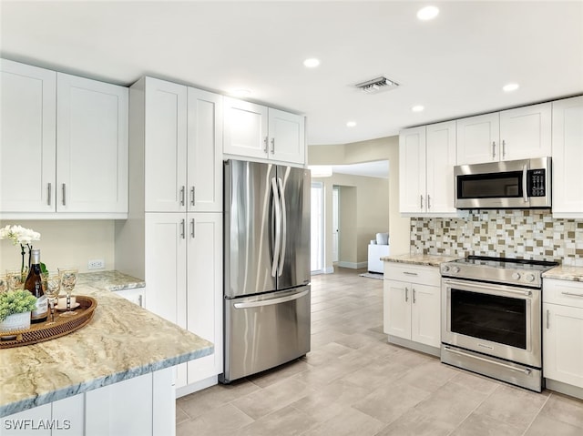 kitchen with light stone countertops, stainless steel appliances, and white cabinetry