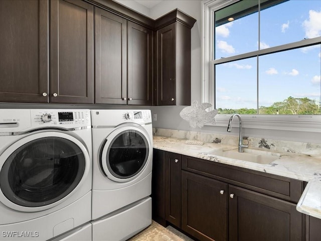 laundry area featuring washing machine and clothes dryer, sink, and cabinets