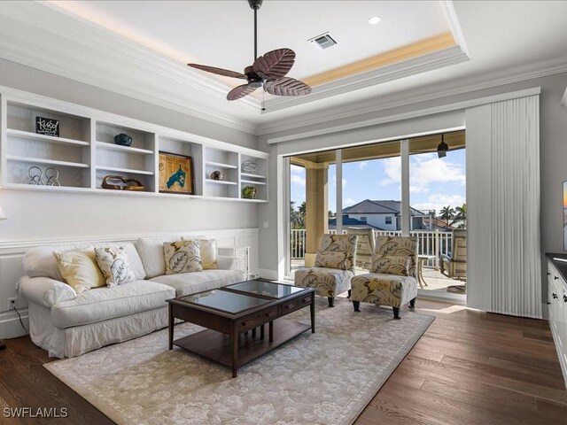 living room with ornamental molding, a raised ceiling, ceiling fan, and dark wood-type flooring