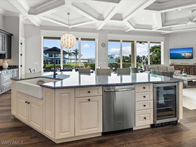 kitchen with ornamental molding, sink, beverage cooler, and an island with sink