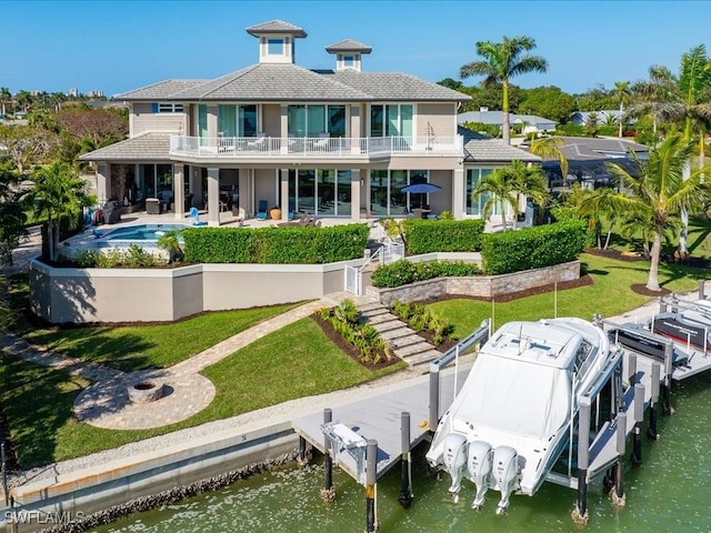 back of property featuring a balcony, a lawn, a patio area, and a water view