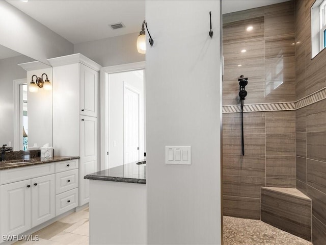 bathroom with tile patterned flooring, vanity, and a tile shower