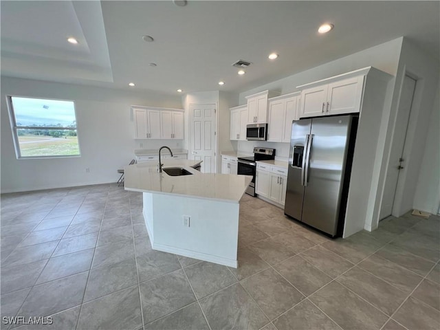 kitchen with a center island with sink, sink, appliances with stainless steel finishes, light tile patterned flooring, and white cabinetry