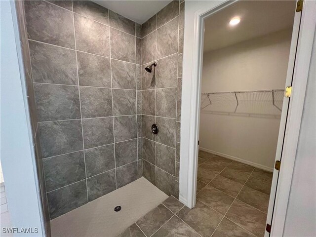 bathroom with tile patterned flooring and a tile shower