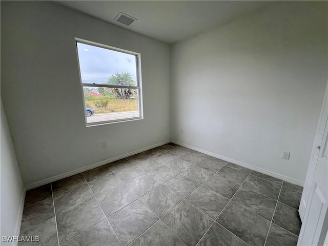 spare room featuring dark tile patterned floors