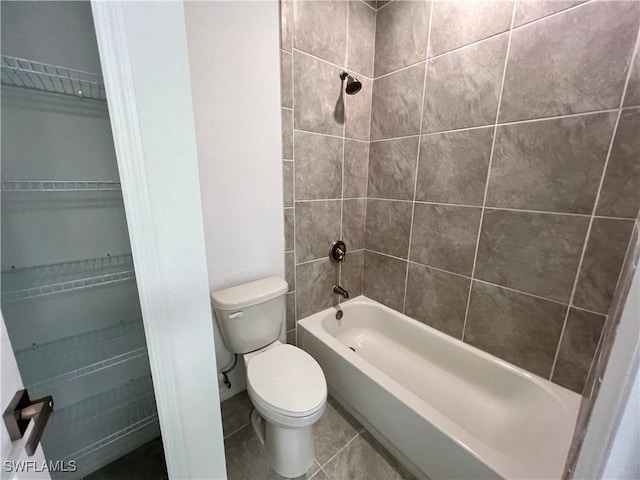 bathroom featuring tile patterned floors, tiled shower / bath combo, and toilet