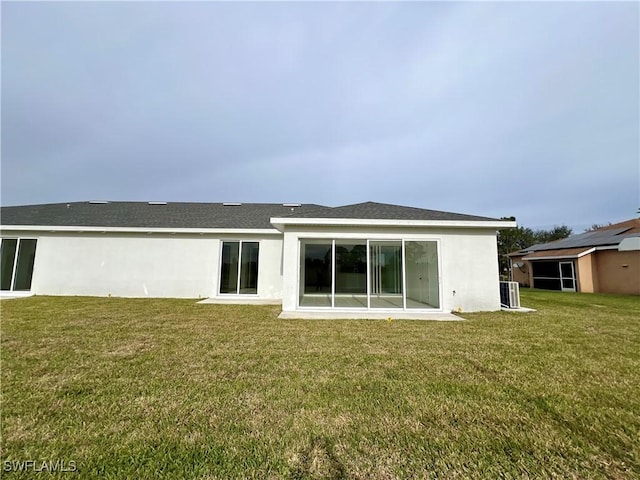 rear view of property with a yard and central AC