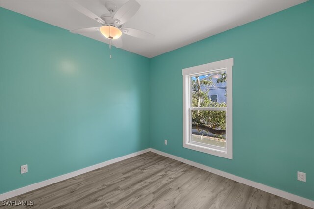 spare room with ceiling fan, light wood-style flooring, and baseboards