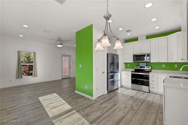 kitchen with open floor plan, stainless steel appliances, hanging light fixtures, and white cabinets