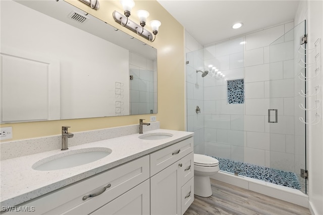 bathroom featuring toilet, visible vents, a sink, and wood finished floors