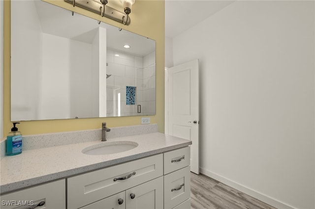 bathroom with a stall shower, baseboards, wood finished floors, and vanity