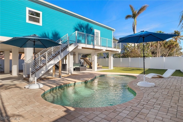 rear view of property featuring a fenced in pool, a patio, fence, a balcony, and stairs