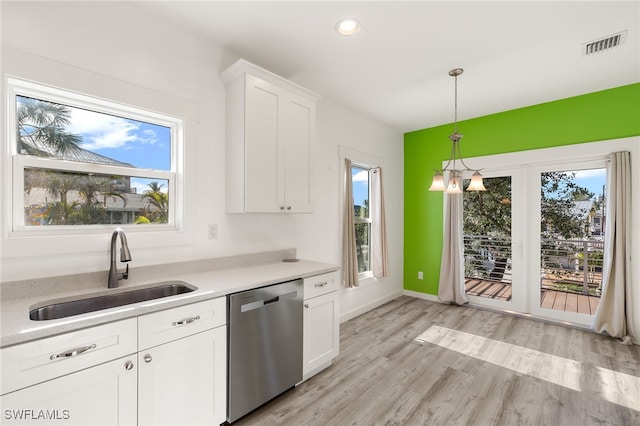 kitchen featuring light countertops, hanging light fixtures, stainless steel dishwasher, white cabinetry, and a sink