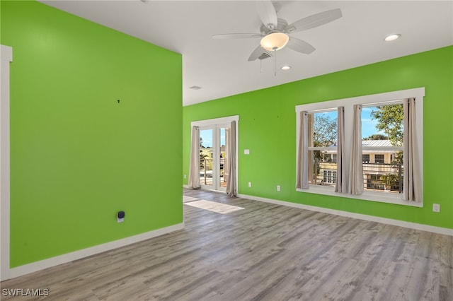 empty room with a ceiling fan, plenty of natural light, light wood-style flooring, and baseboards