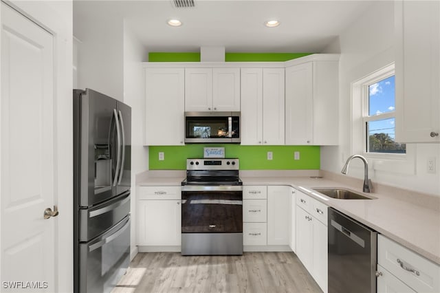 kitchen with light wood-style flooring, recessed lighting, stainless steel appliances, a sink, and white cabinetry