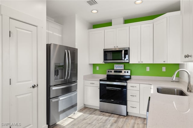 kitchen featuring visible vents, appliances with stainless steel finishes, a sink, and white cabinetry