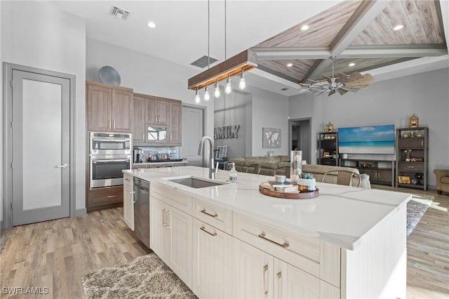 kitchen featuring a large island, sink, ceiling fan, beamed ceiling, and decorative light fixtures