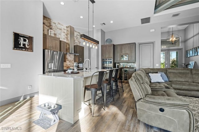 kitchen with stainless steel fridge, a spacious island, hanging light fixtures, and a breakfast bar area