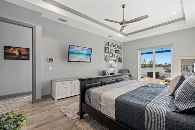 bedroom featuring ceiling fan, a raised ceiling, light wood-type flooring, access to outside, and ornamental molding