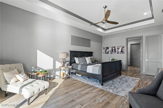 bedroom with a tray ceiling, ceiling fan, and wood-type flooring