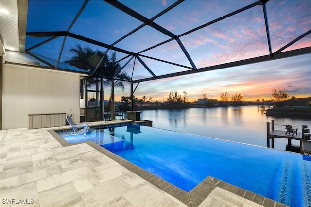 pool at dusk with a patio, a water view, and glass enclosure