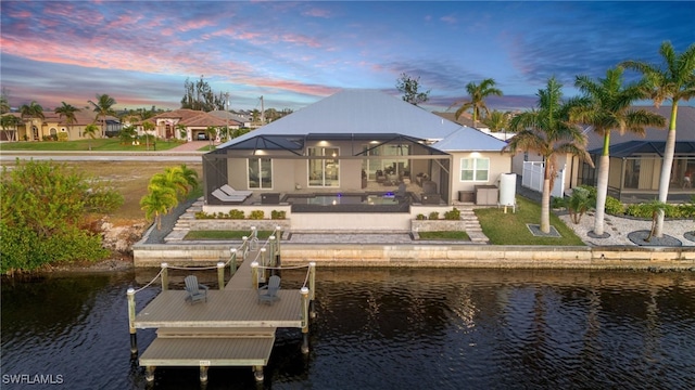 back house at dusk featuring a patio area, a water view, and a yard