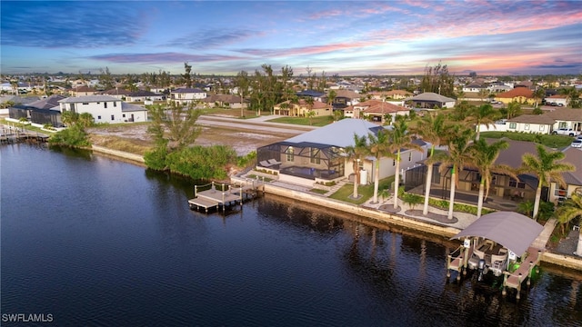 aerial view at dusk featuring a water view