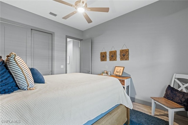 bedroom with hardwood / wood-style flooring, ceiling fan, and a closet