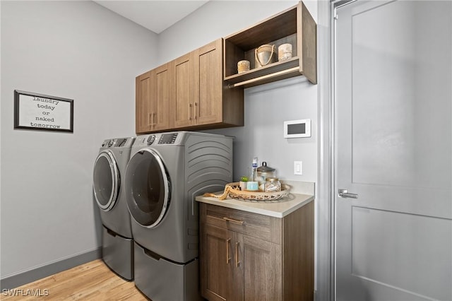 laundry room with separate washer and dryer, cabinets, and light wood-type flooring