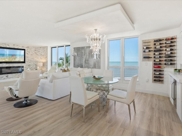 dining area featuring light wood-type flooring, a chandelier, and a water view