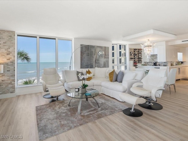 living room featuring a water view, a beach view, a chandelier, and light hardwood / wood-style flooring