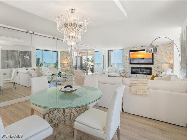 dining space featuring a notable chandelier, a stone fireplace, and light hardwood / wood-style flooring