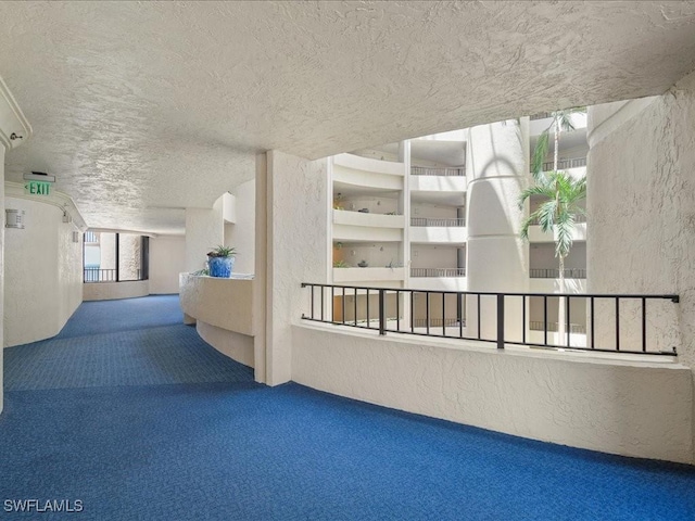 hall with carpet floors and a textured ceiling